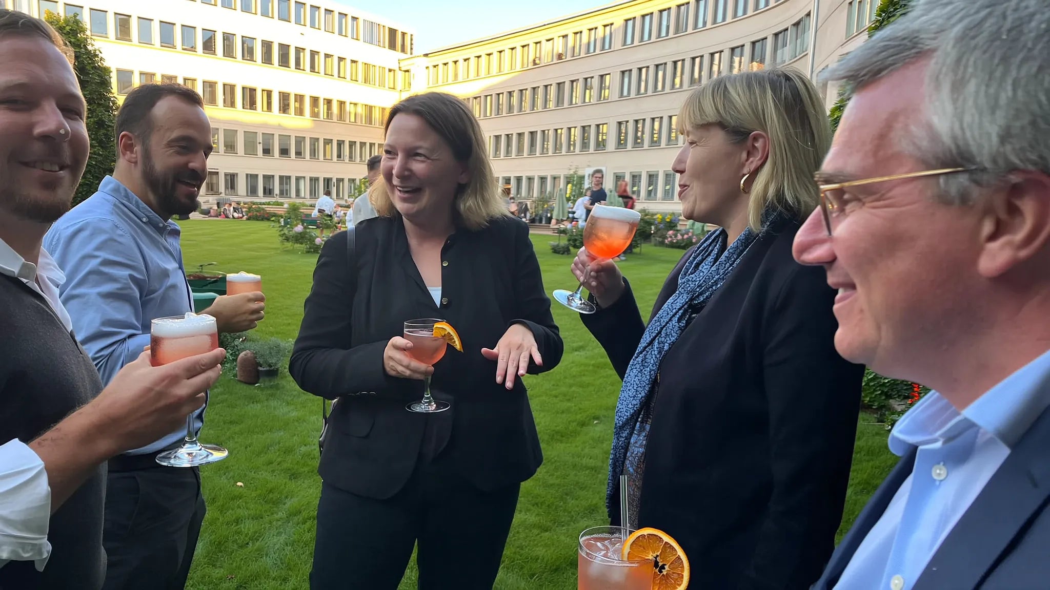 Kollegen stoßen bei der Firmenfeier im Innenhof mit Sankt Sprizz an (Symbolbild)